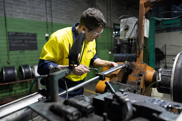 Fitter & turner wearing PPE performing maintenance and repairs on a machine.